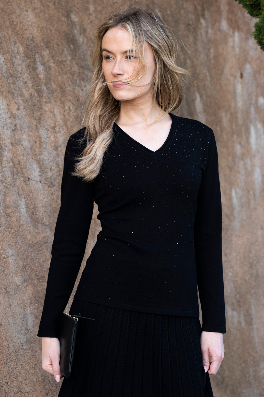 Woman wearing a black long-sleeve top against a brown wall
