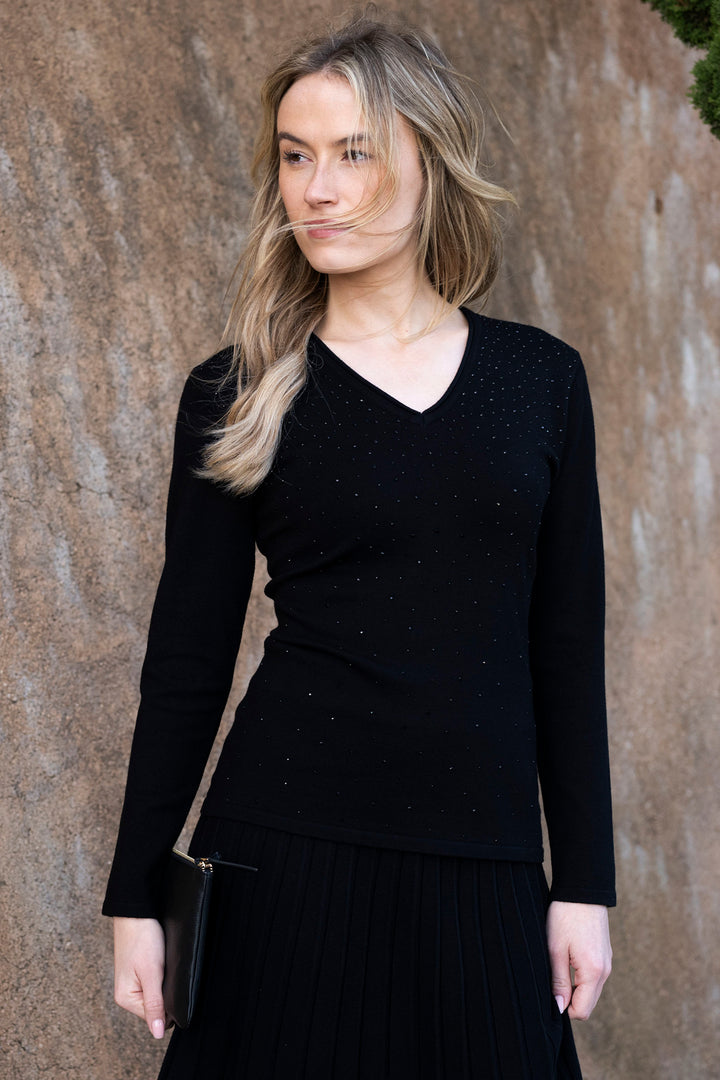 Woman wearing a black long-sleeve top against a brown wall
