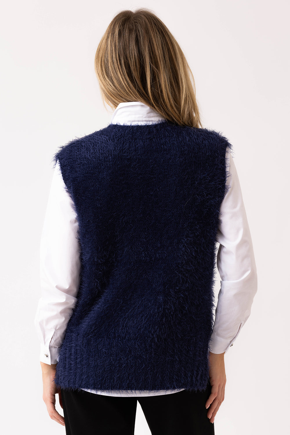 Person wearing a navy blue vest over a white shirt on a plain background