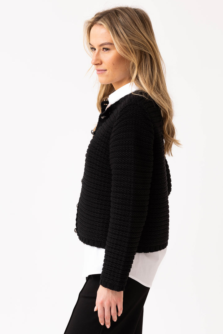 Woman wearing a black textured sweater over a white shirt on a white background