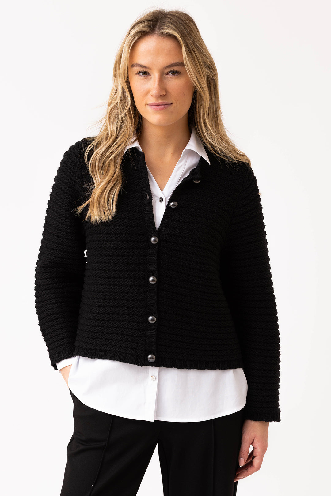 Woman wearing a black textured cardigan over a white shirt on a white background