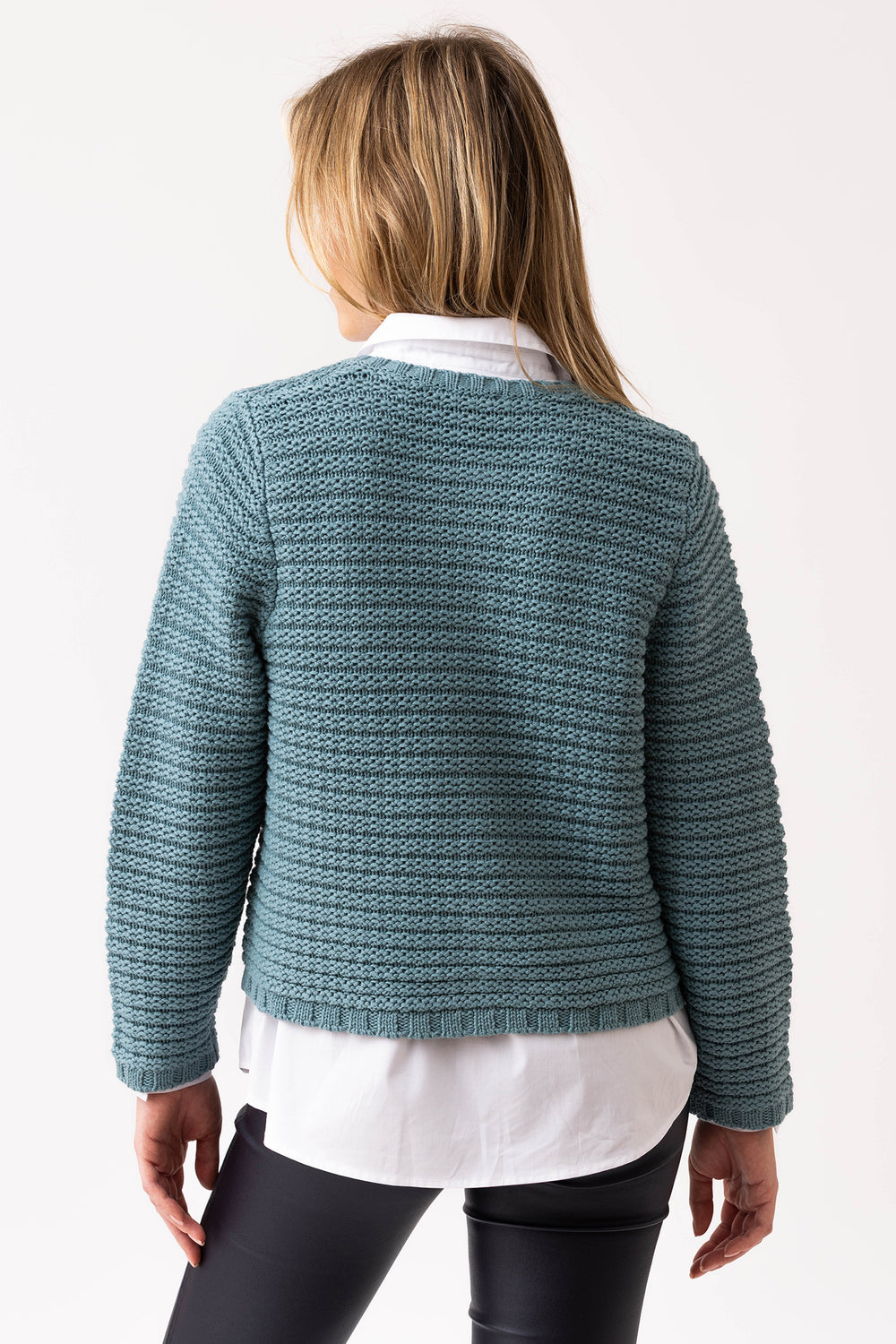 Person wearing a teal knitted cardigan on a white background