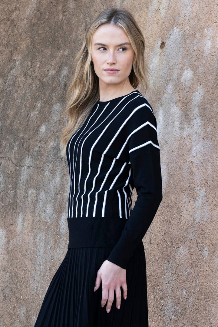 Woman wearing a black dress with white stripes against a textured beige wall