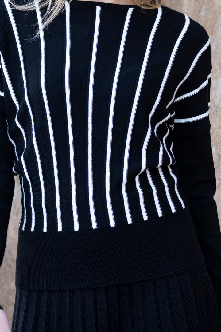 Black sweater with white vertical stripes worn by a person against a neutral background