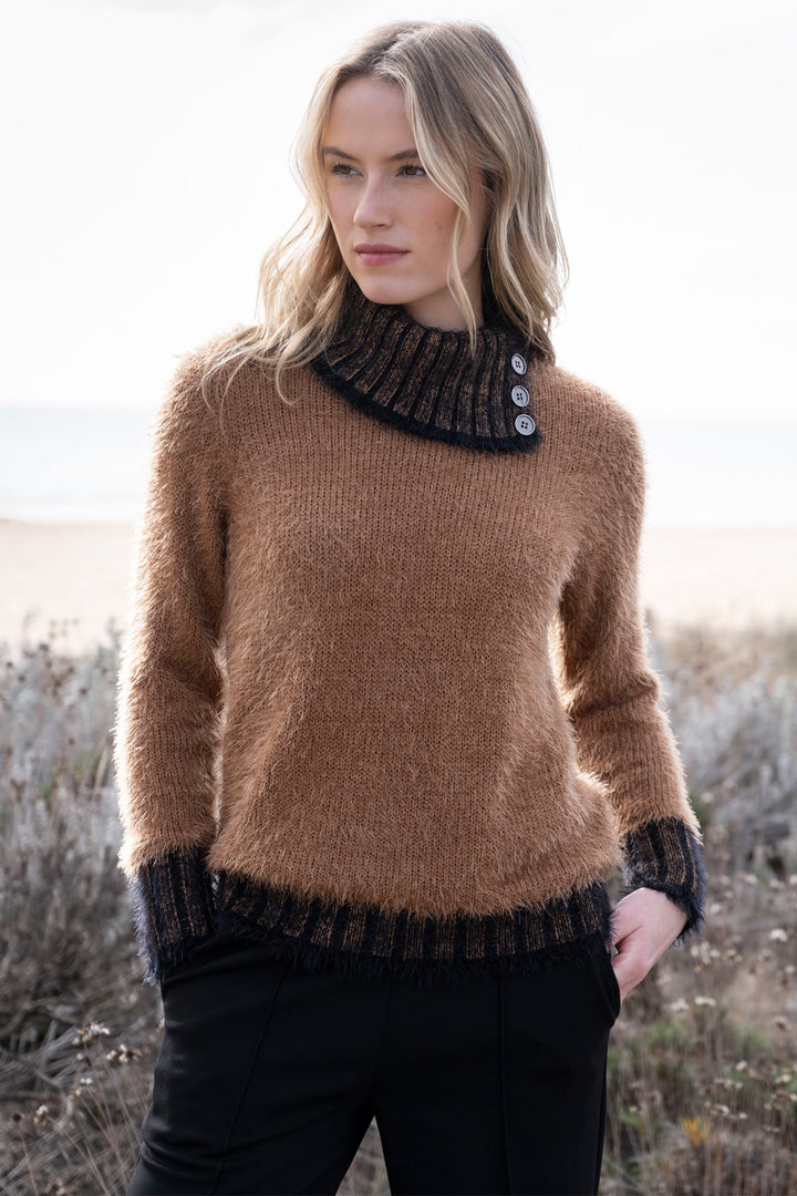 Woman wearing a brown sweater with black ribbed trim in a natural setting