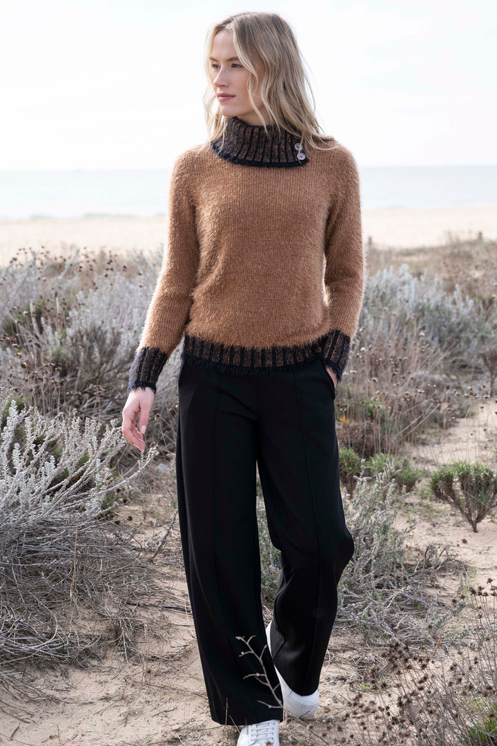 Woman wearing a brown sweater and black pants in a desert setting