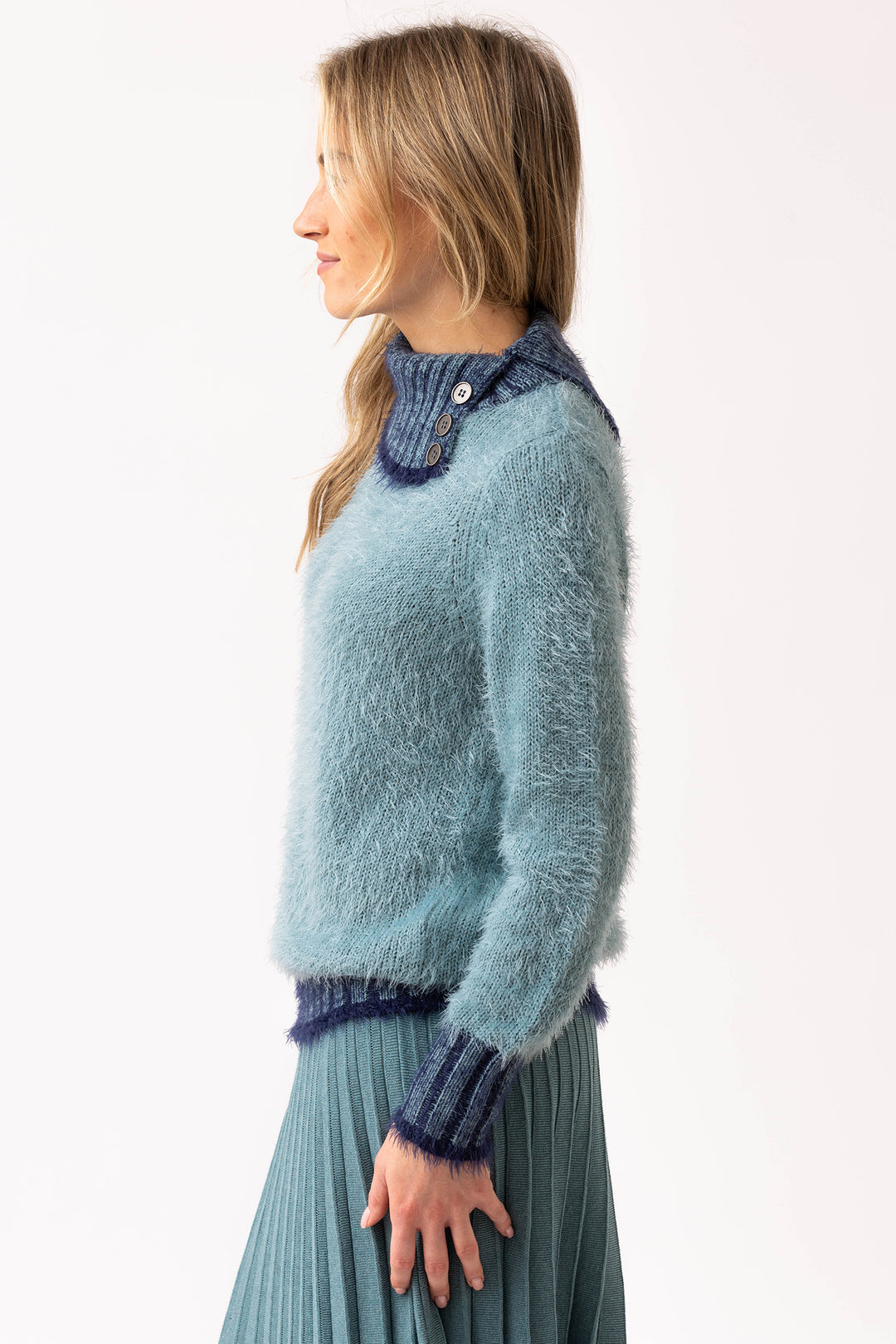 Woman wearing a light blue sweater with dark blue trim on a white background