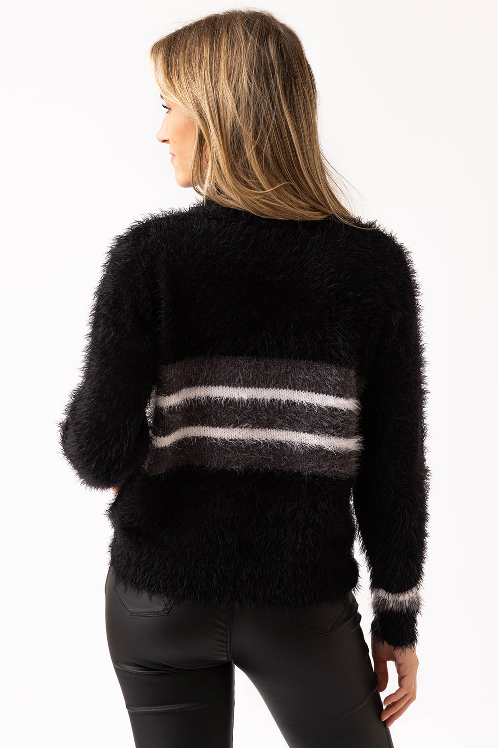 Woman wearing a black fuzzy sweater with gray and white stripes on a white background