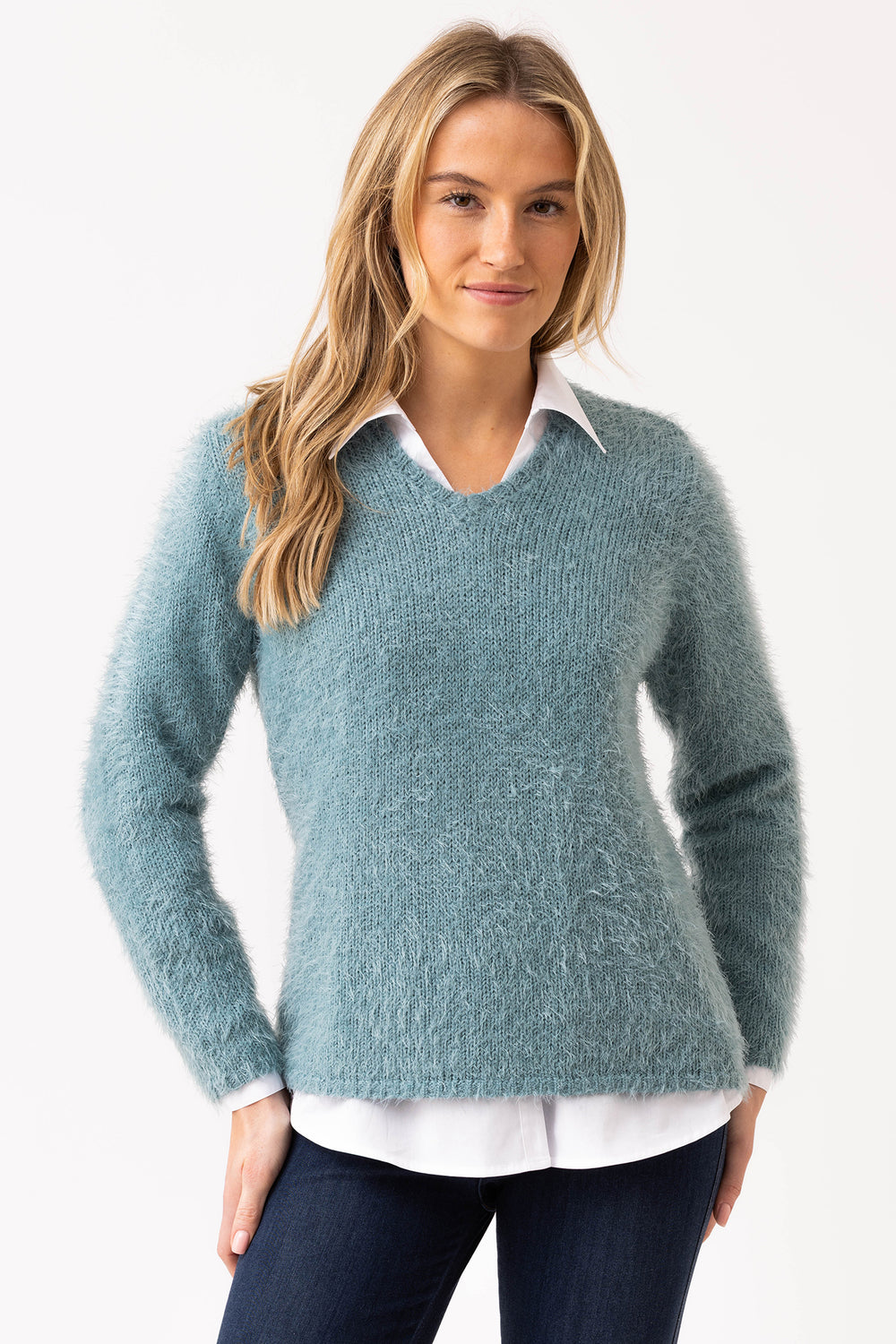 Woman wearing a teal sweater over a white shirt on a white background