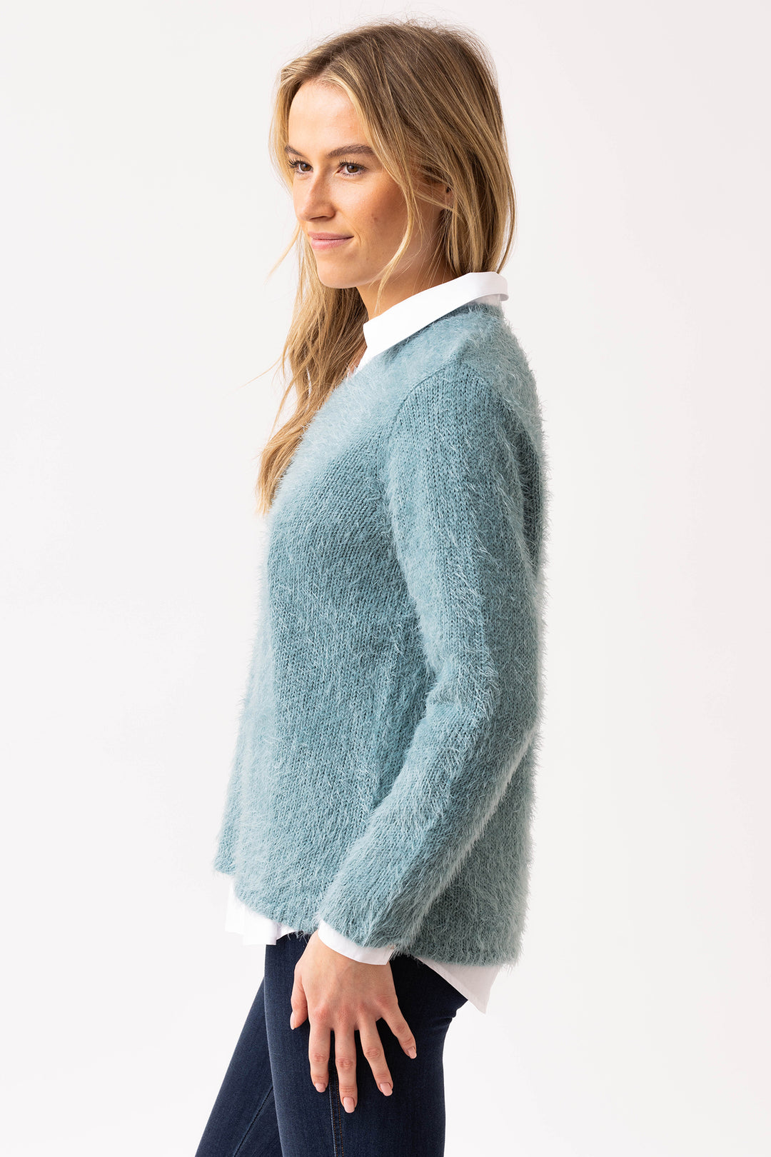 Woman wearing a light blue sweater over a white shirt on a white background