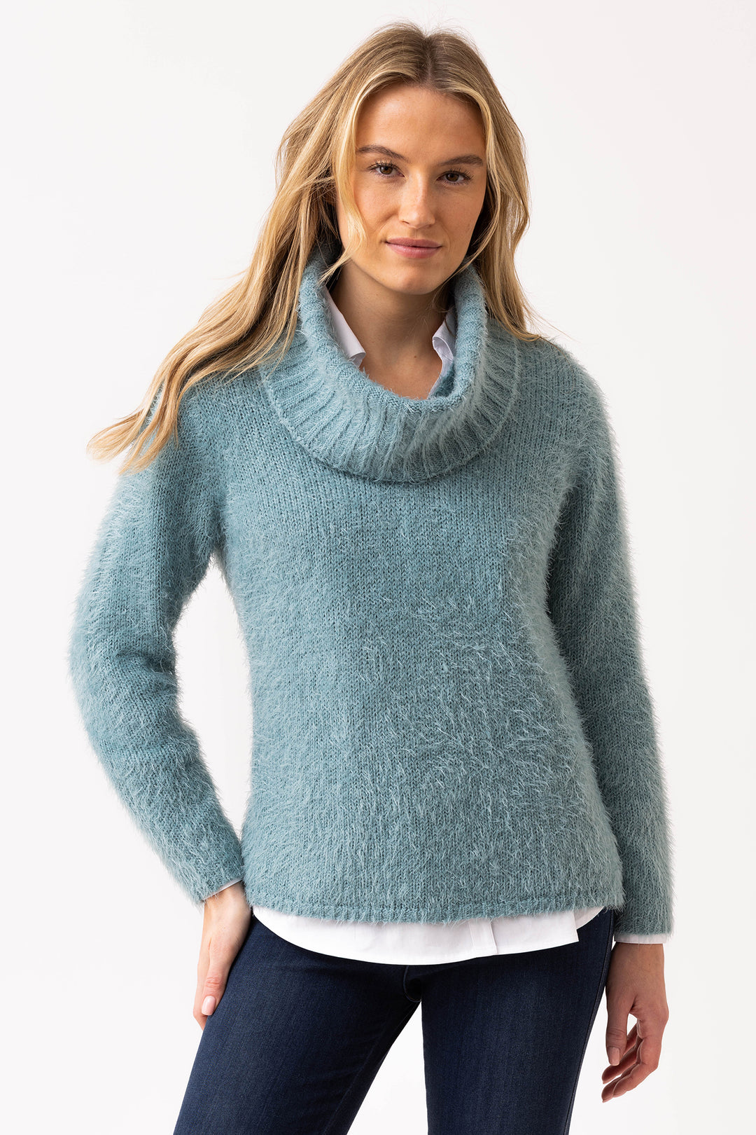 Woman wearing a teal sweater with a white shirt underneath on a light gray background