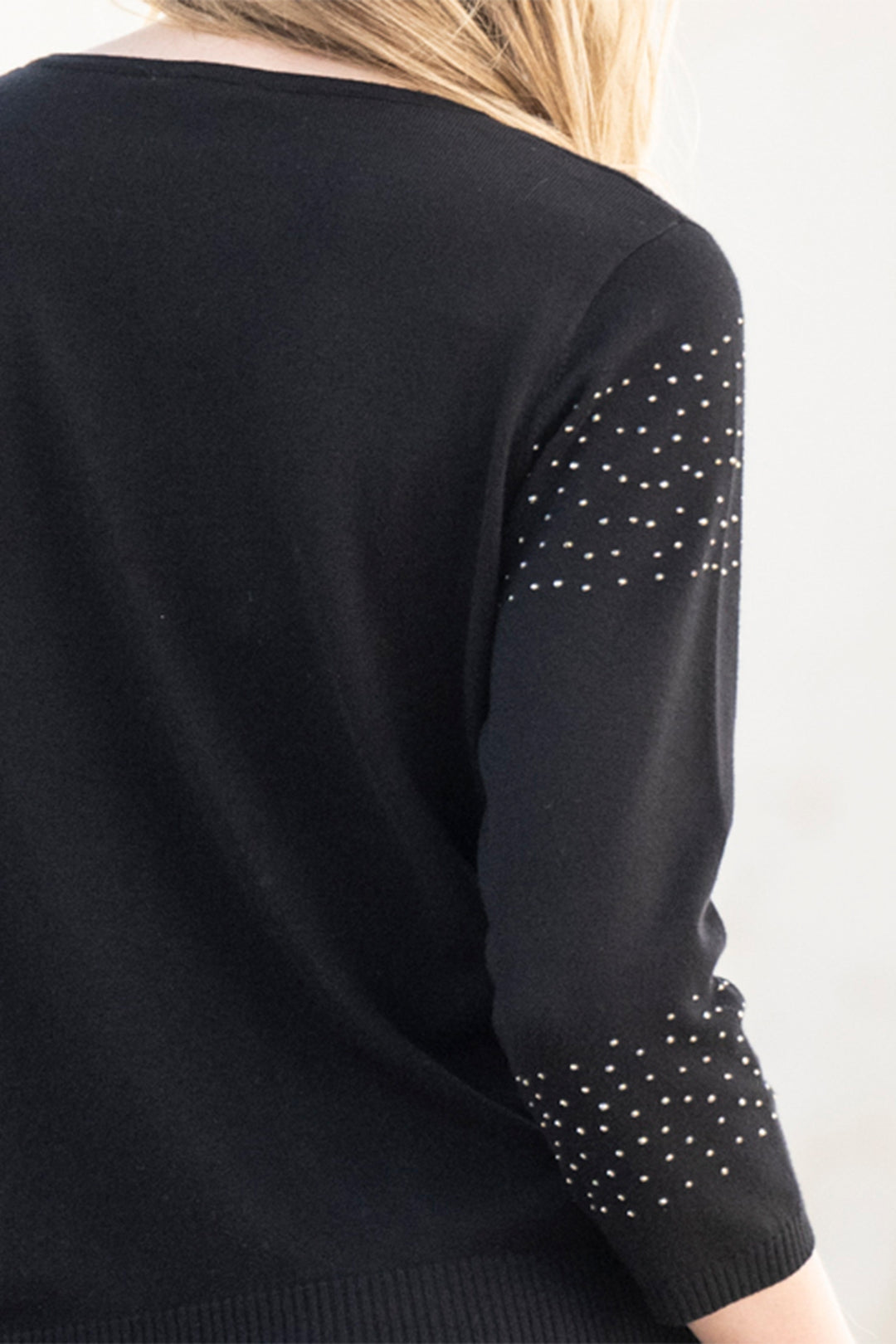 Black sweater with polka dot pattern on sleeves against a white background
