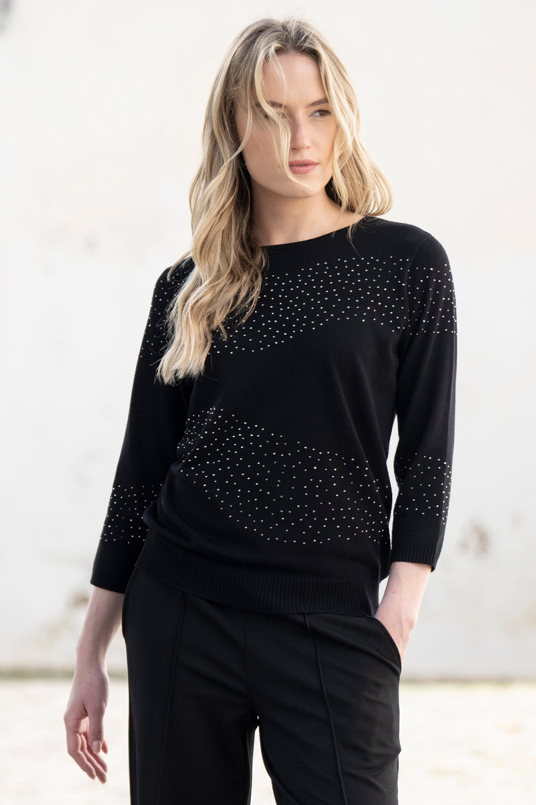 Woman wearing a black sweater with decorative elements against a white background