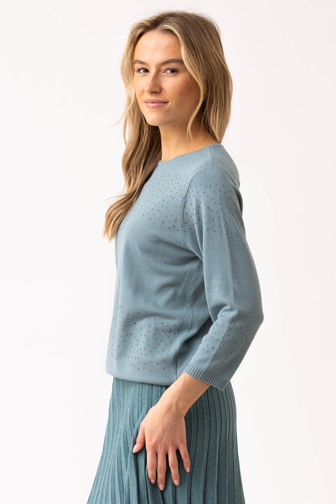 Woman wearing a light blue sweater and skirt on a white background