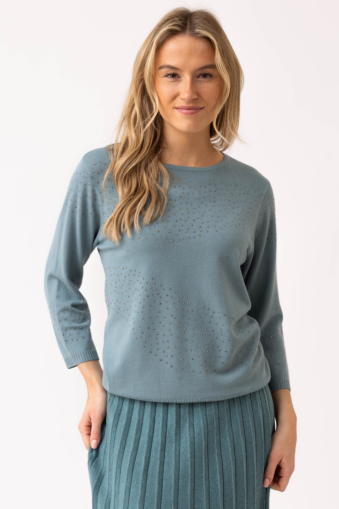 Woman wearing a light blue sweater with a subtle pattern on a white background