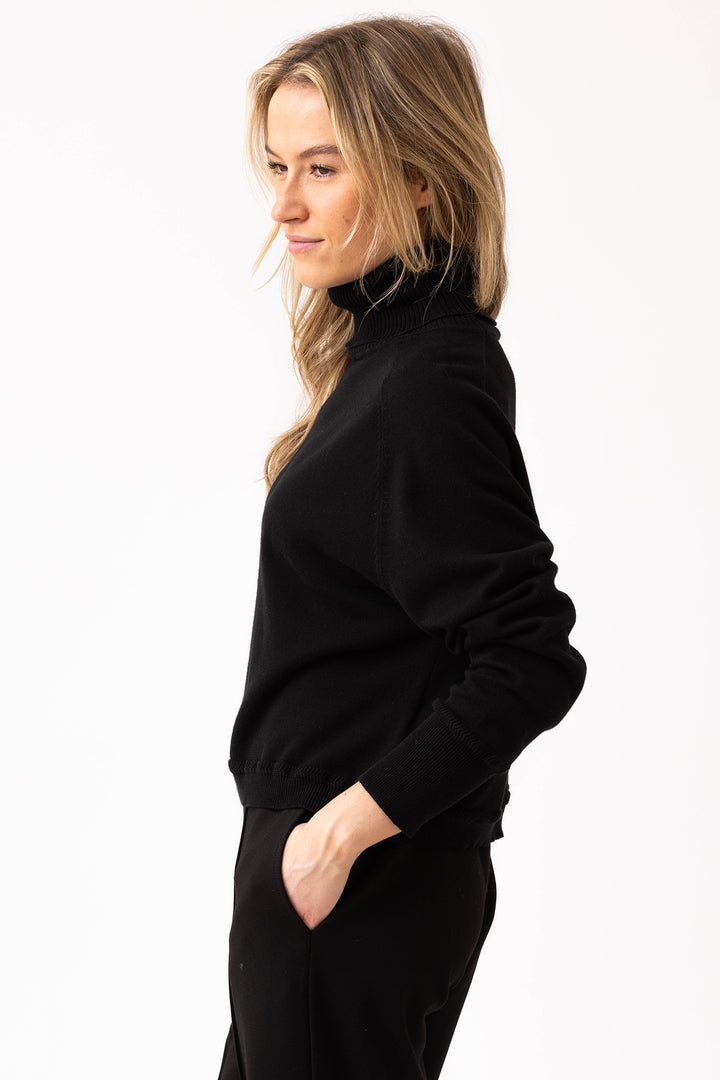 Woman wearing a black turtleneck sweater on a white background