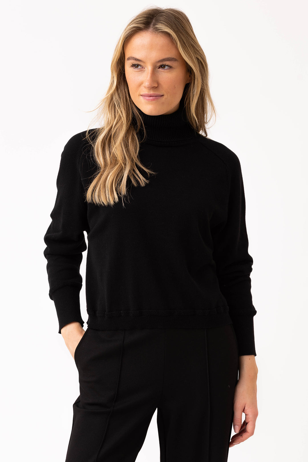 Woman wearing a black turtleneck sweater and pants on a white background