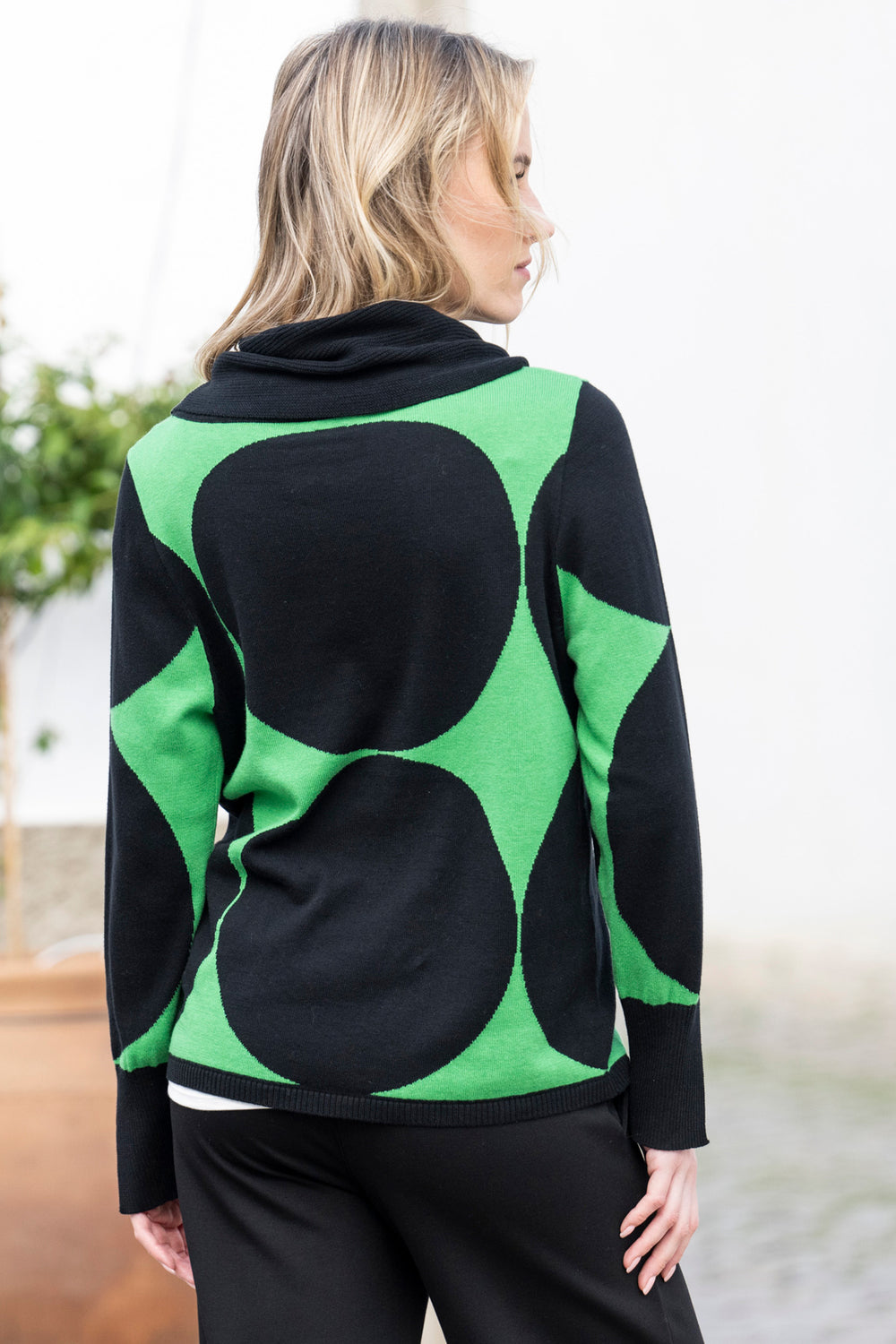 Woman wearing a black and green patterned sweater with a blurred background