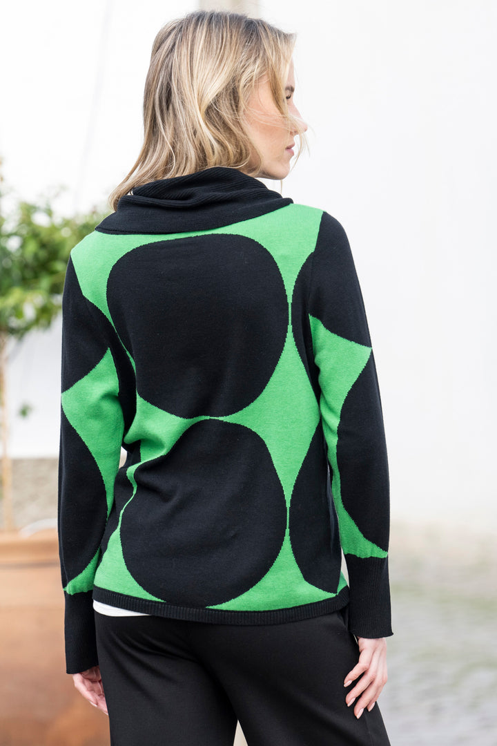 Woman wearing a black and green patterned sweater with a blurred background