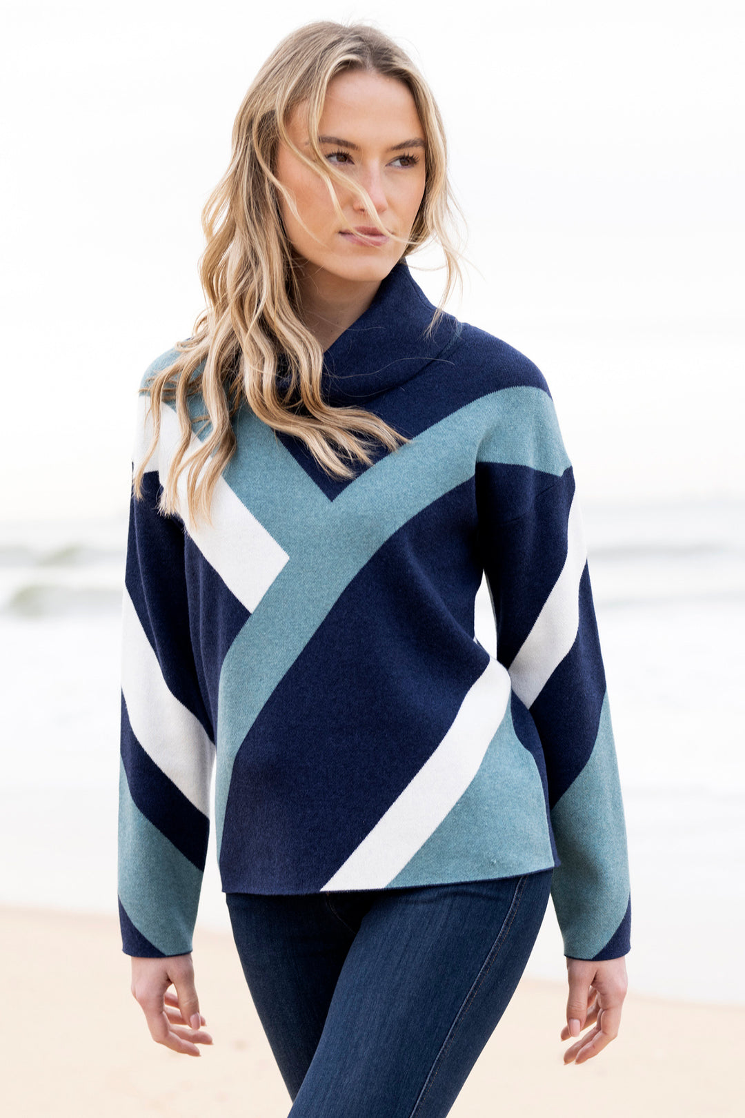 Woman wearing a blue and white patterned sweater on a beach.