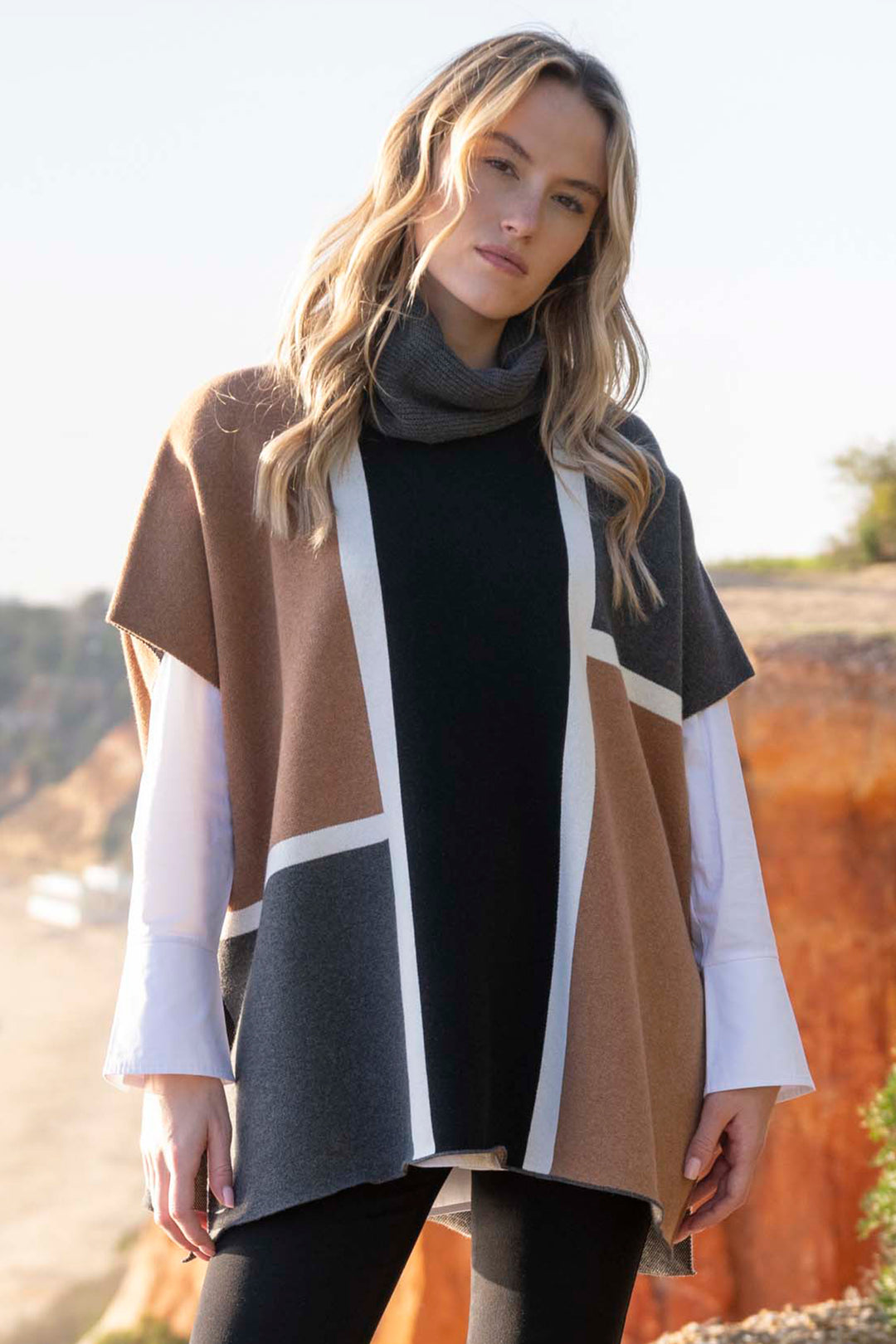 Woman wearing a color-blocked poncho with a scenic background