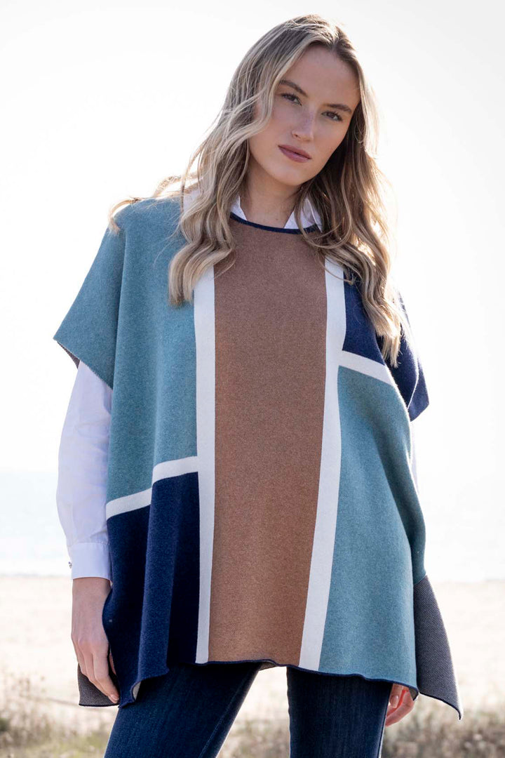 Woman wearing a color-blocked poncho with blue, brown, and white sections.