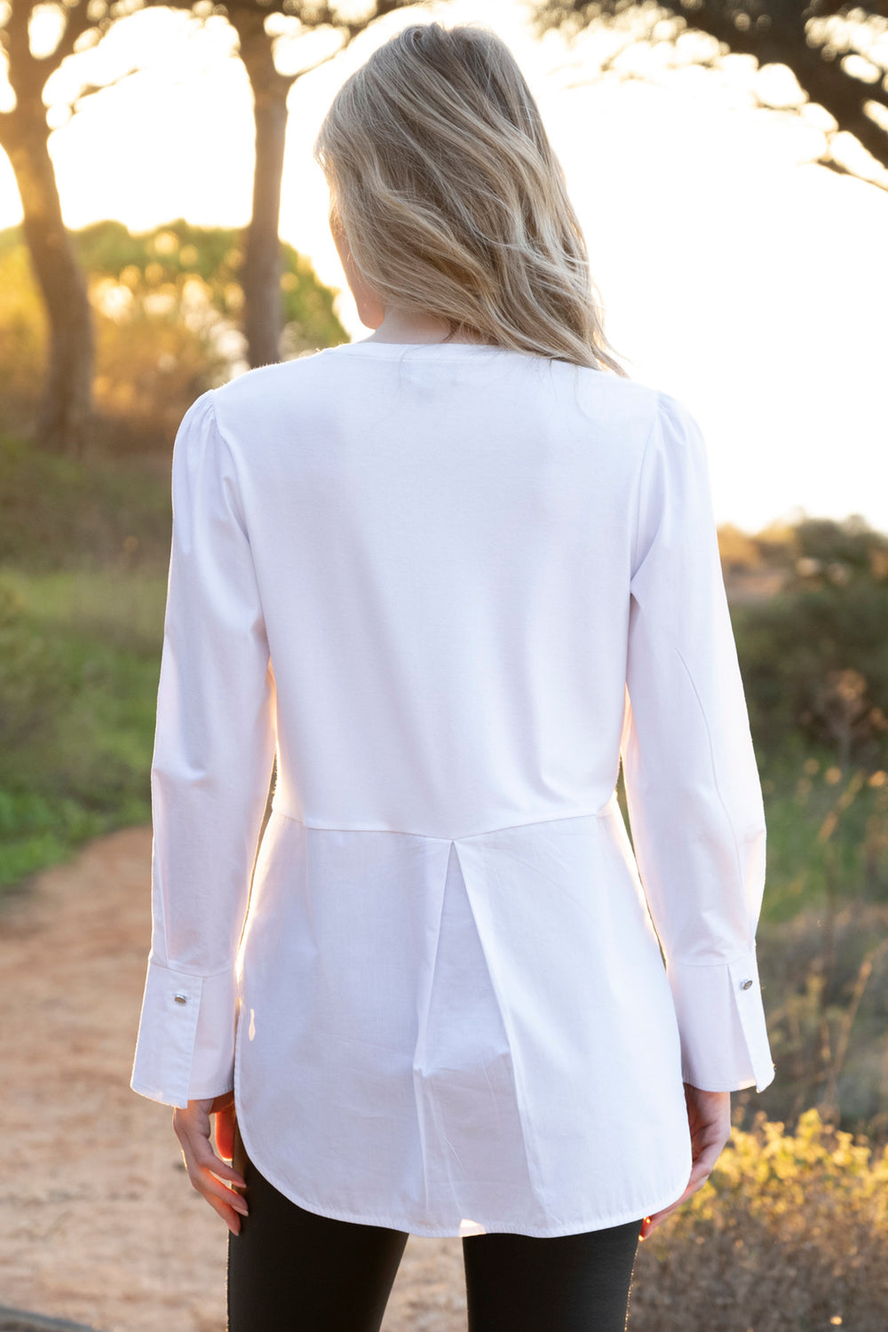 Person wearing a white blazer with a blurred natural background
