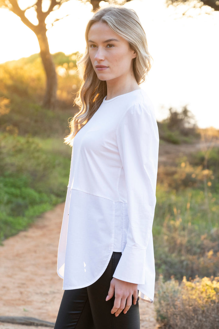 Woman wearing a white blouse standing outdoors with a natural background