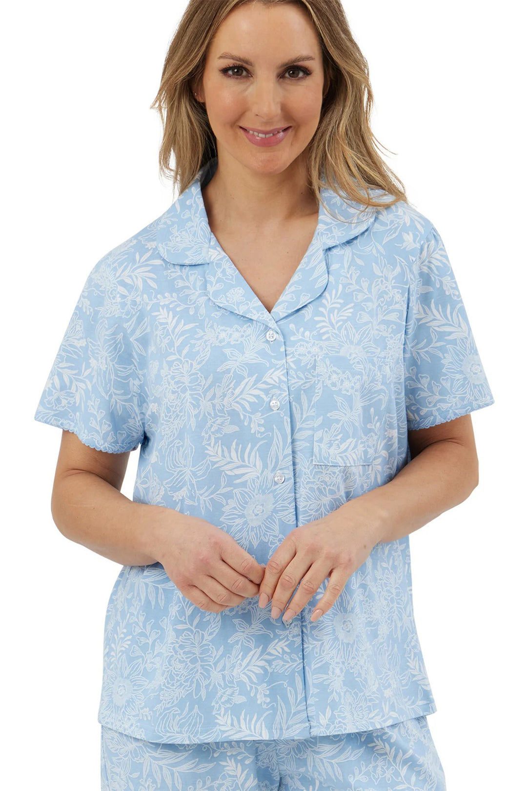 Woman wearing a light blue pajama set with a floral pattern on a white background