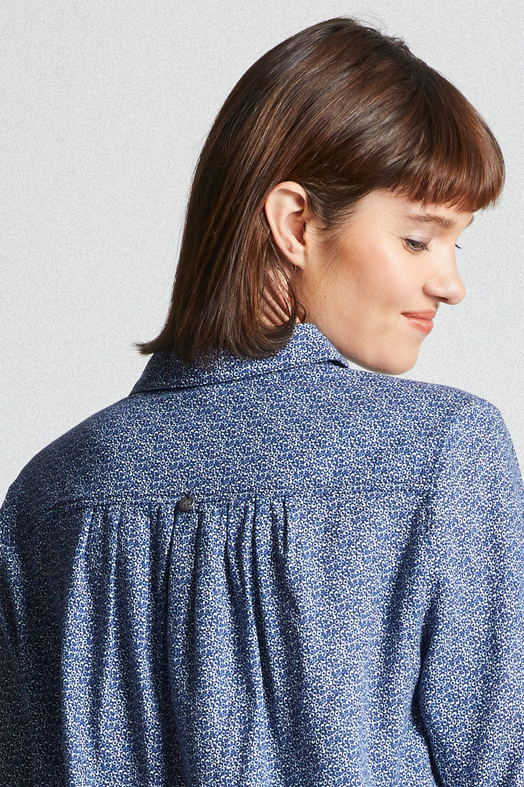 Woman wearing a blue patterned shirt against a light gray background