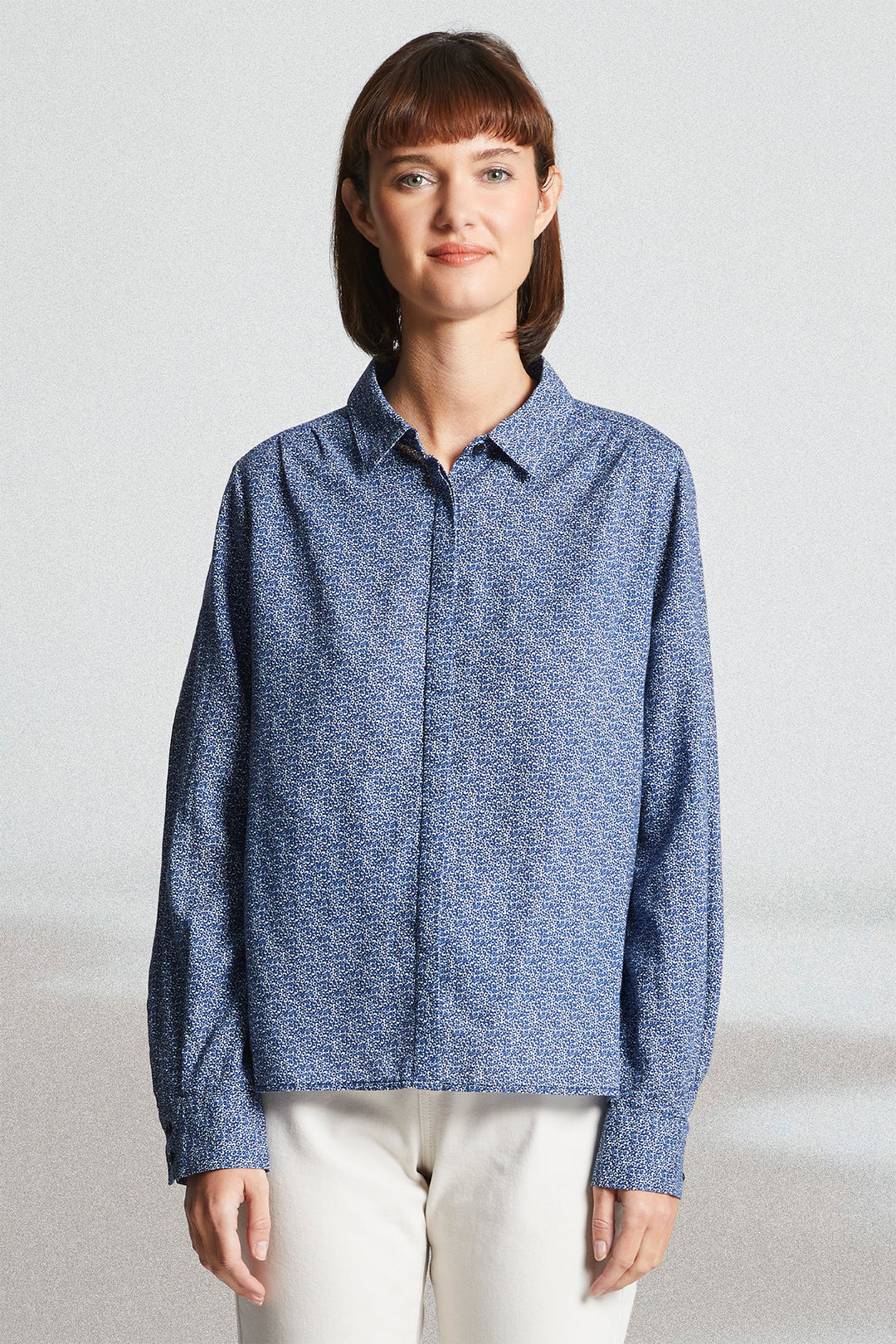 Woman wearing a blue textured shirt against a plain background