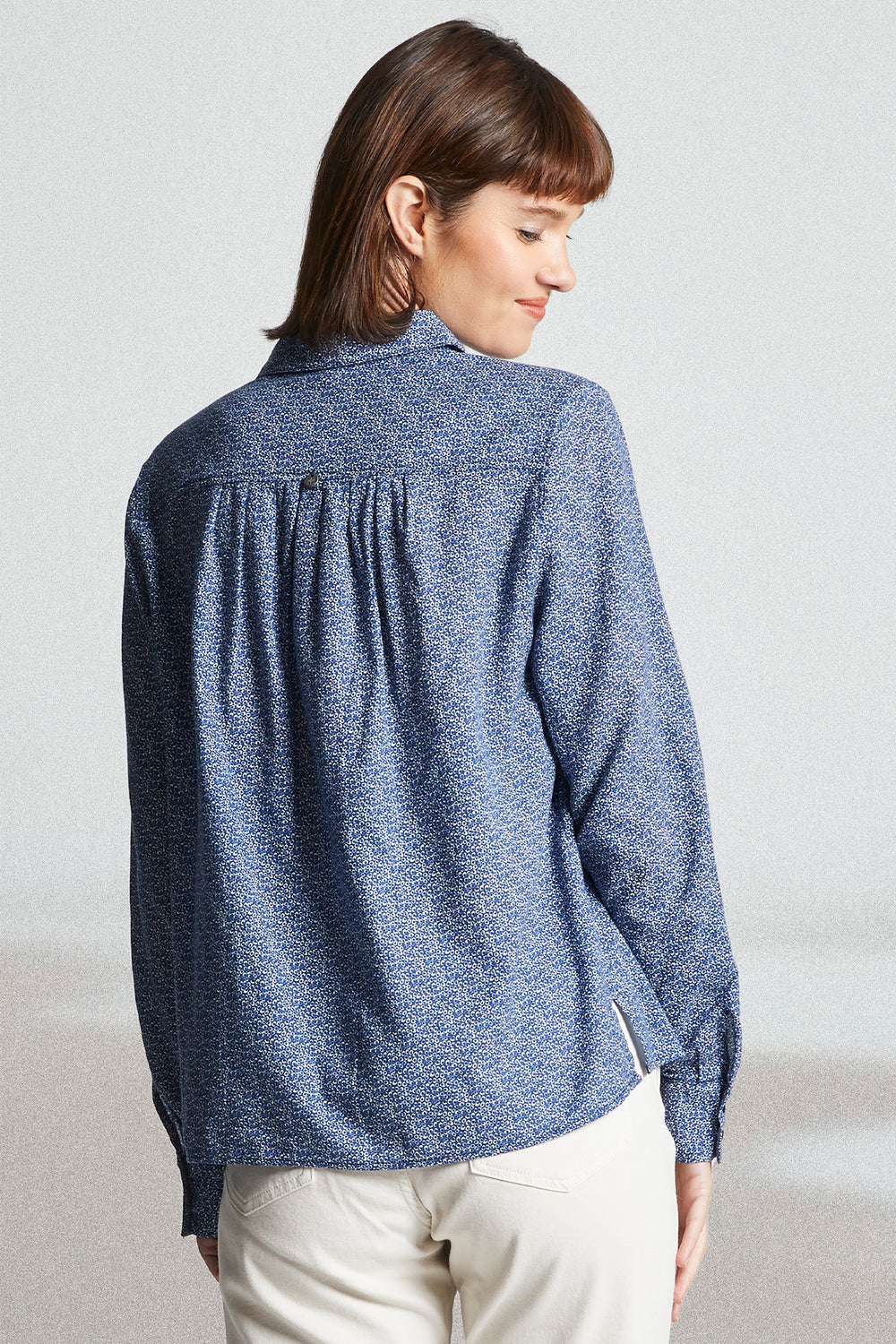 Woman wearing a blue textured shirt against a plain background
