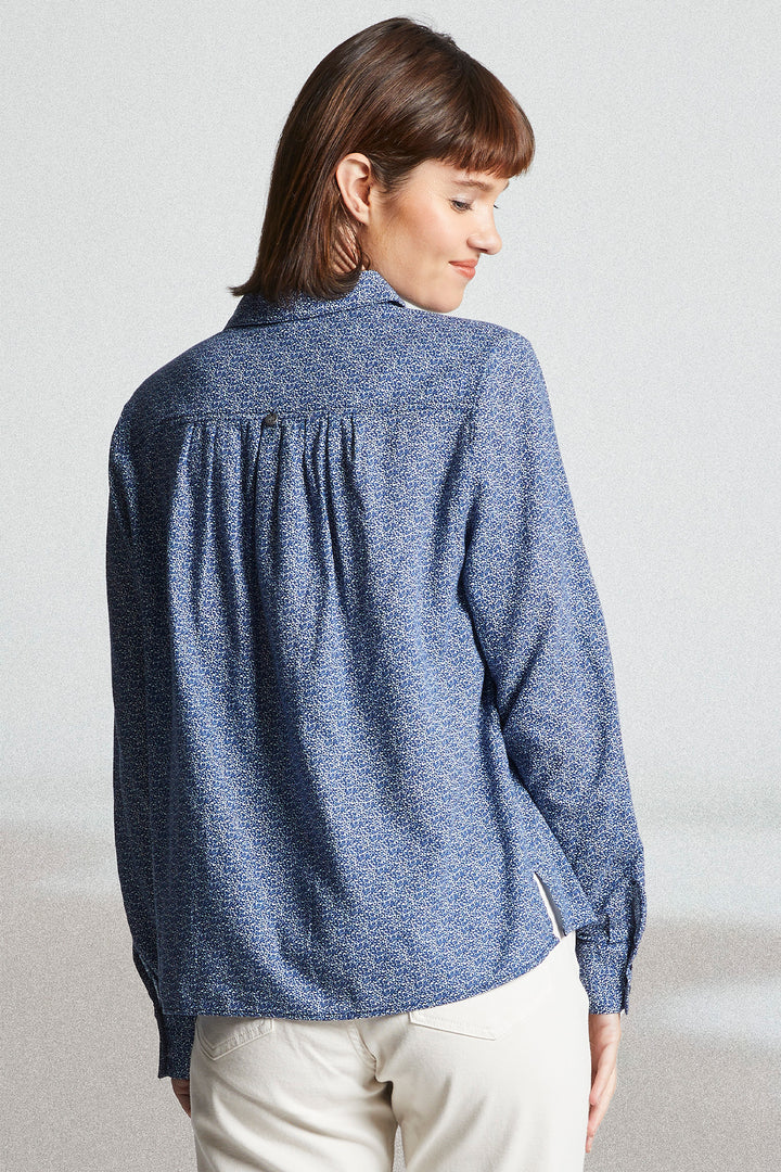 Woman wearing a blue textured shirt against a plain background