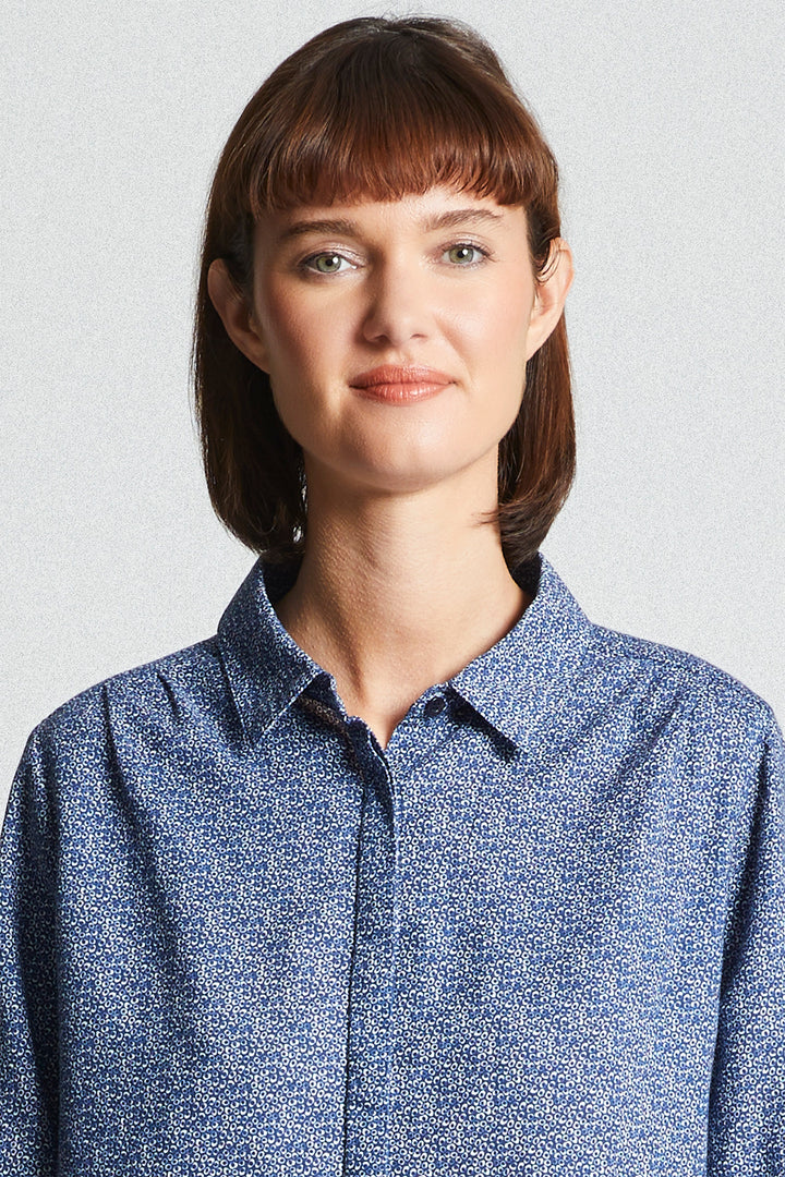 Woman wearing a blue patterned shirt against a light gray background