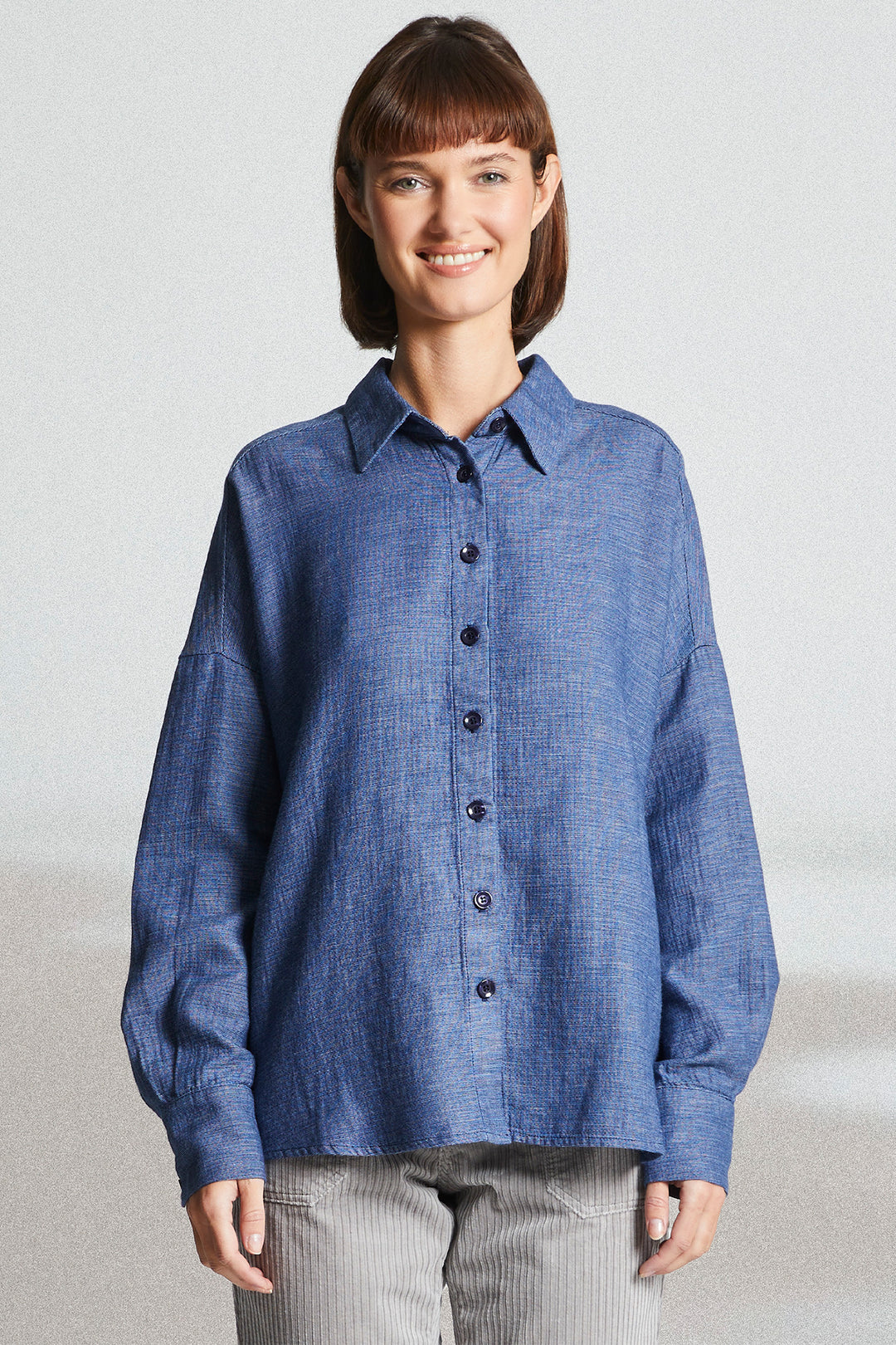 Woman wearing a blue button-up shirt against a plain background