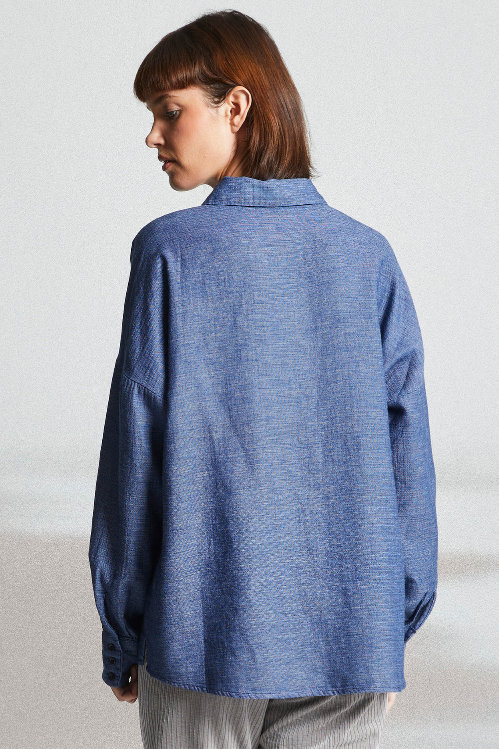 Person wearing a blue textured shirt against a plain background
