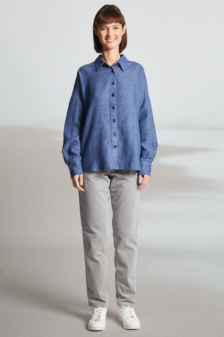Person wearing a blue shirt and gray pants on a plain background