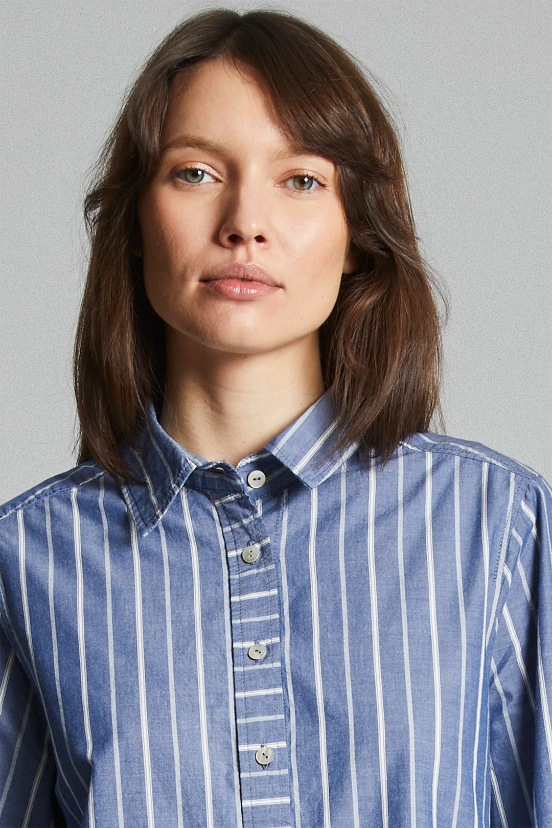 Woman wearing a blue and white striped shirt against a gray background