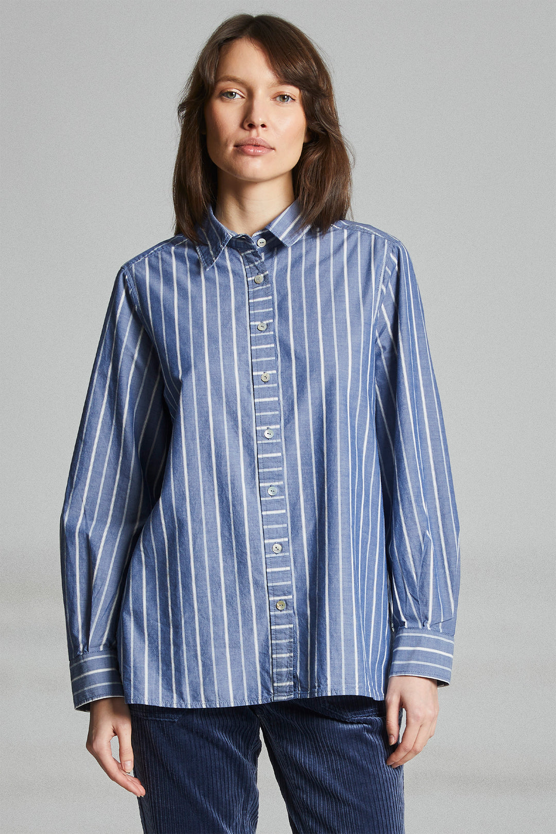 Woman wearing a blue striped shirt against a gray background