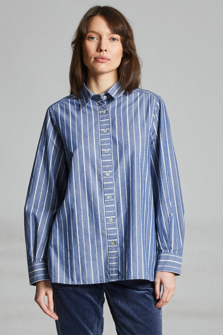 Woman wearing a blue striped shirt against a gray background