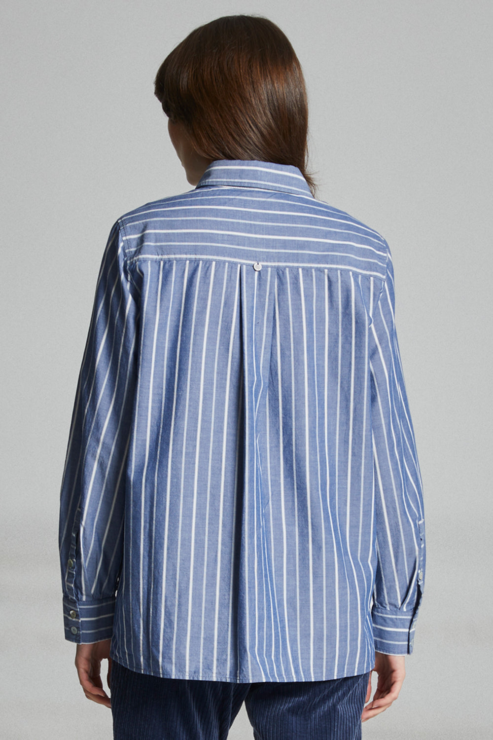 Person wearing a blue and white striped shirt against a gray background