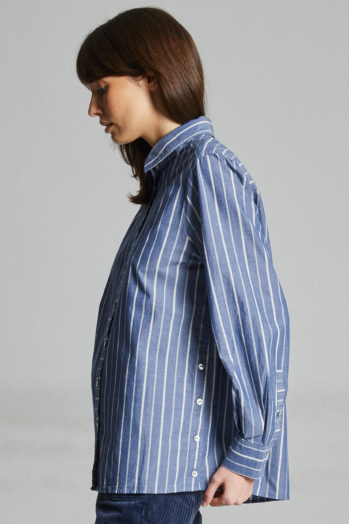 Woman wearing a blue and white striped shirt against a gray background