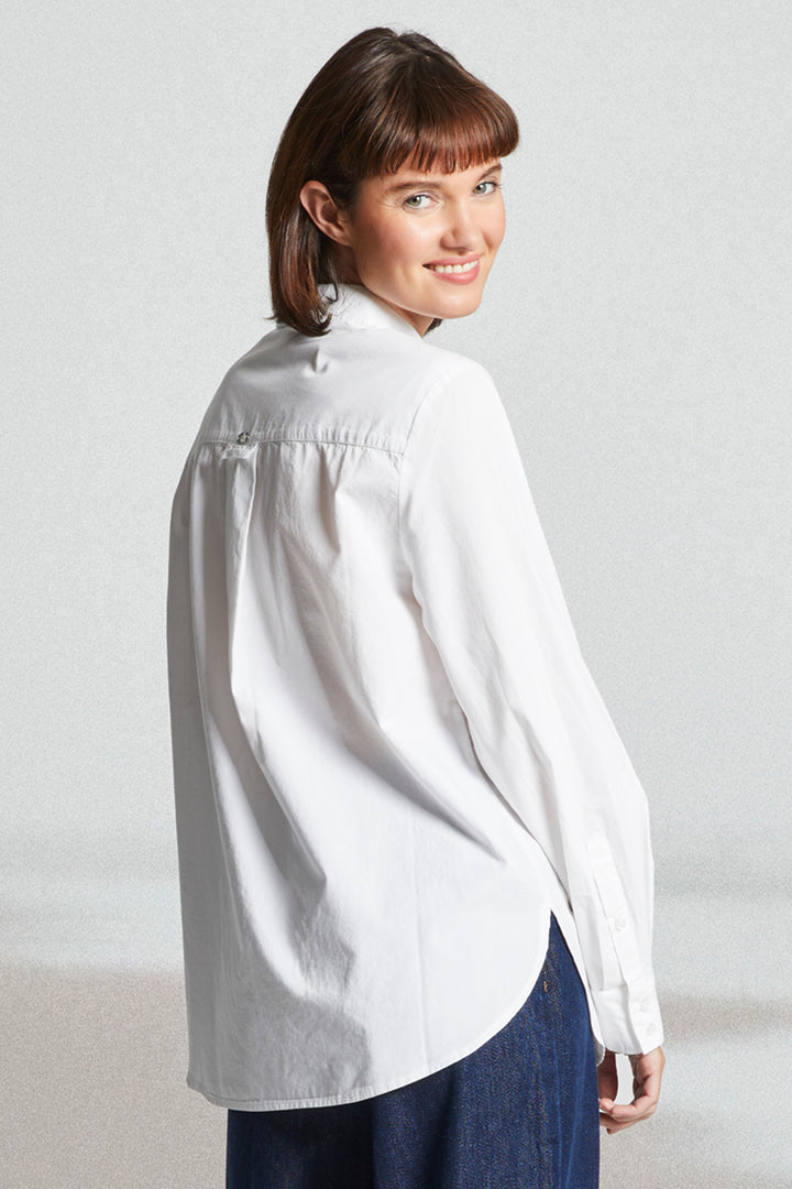 Woman wearing a white shirt and blue pants against a plain background