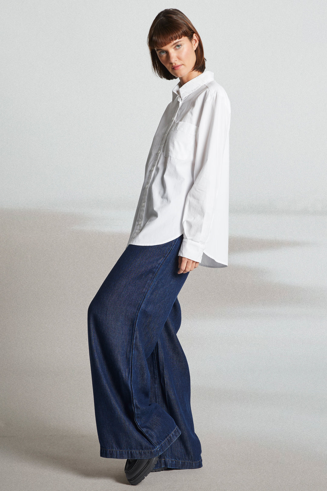 Person wearing a white shirt and blue pants on a plain background