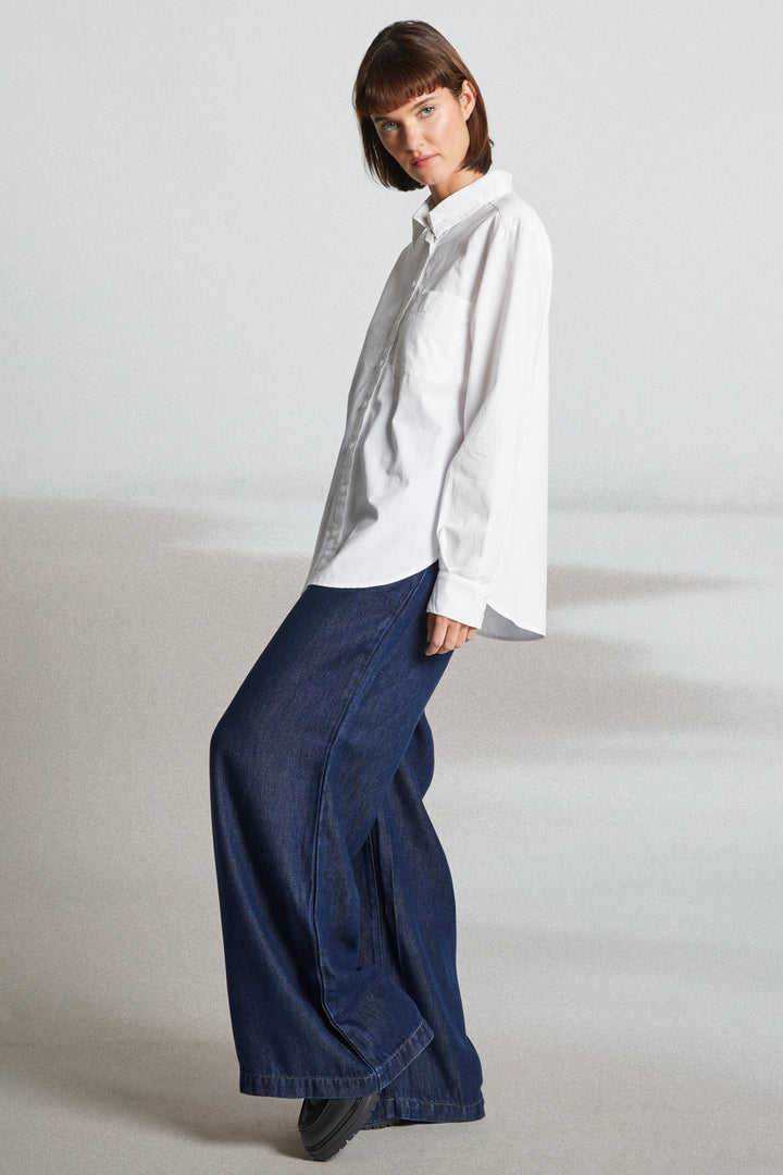 Person wearing a white shirt and blue pants on a plain background