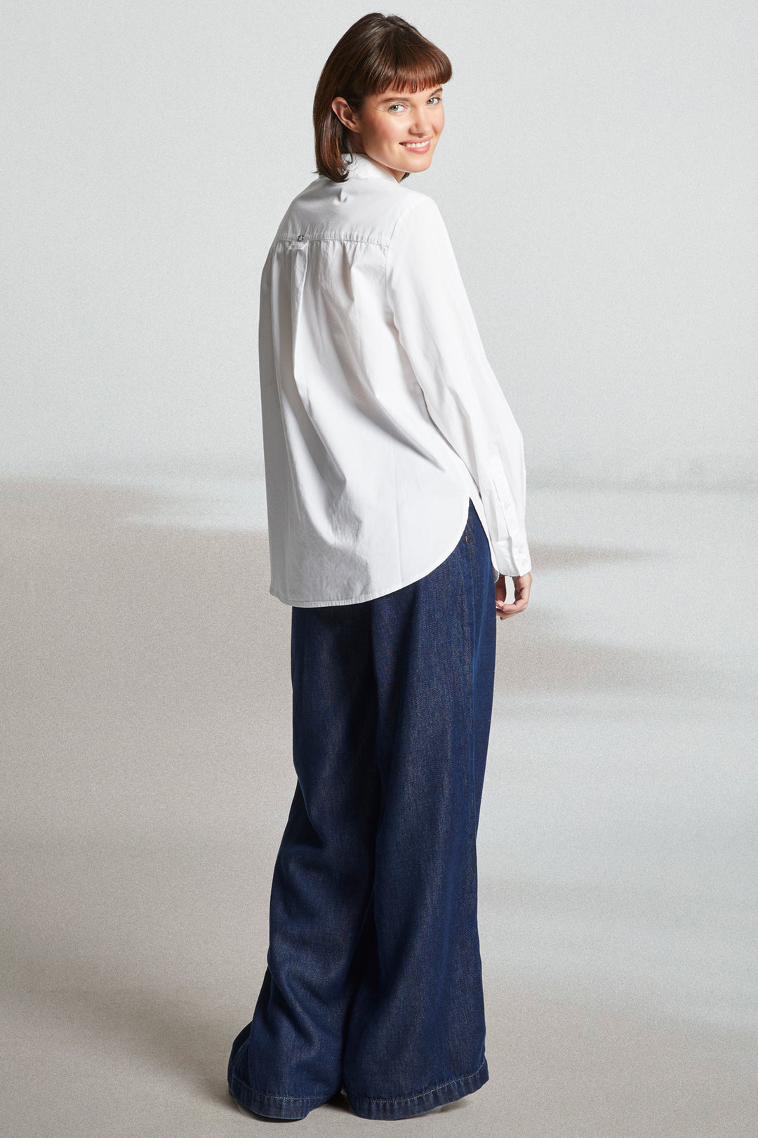 Person wearing a white shirt and blue pants on a plain background