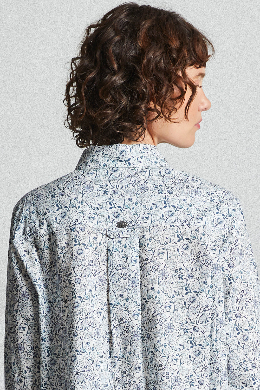 Person wearing a floral patterned shirt against a plain background