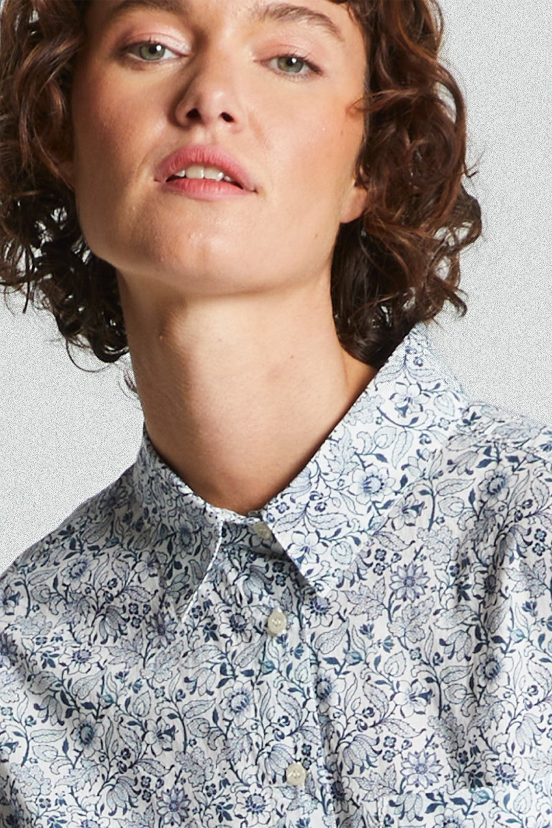 Person wearing a patterned shirt against a plain background
