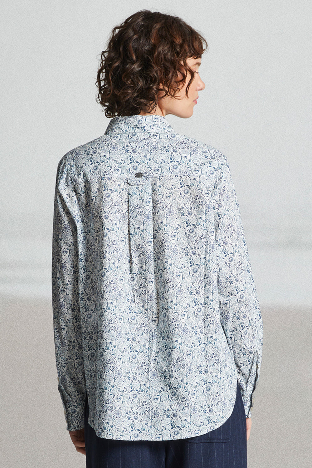 Person wearing a light blue floral shirt against a plain background
