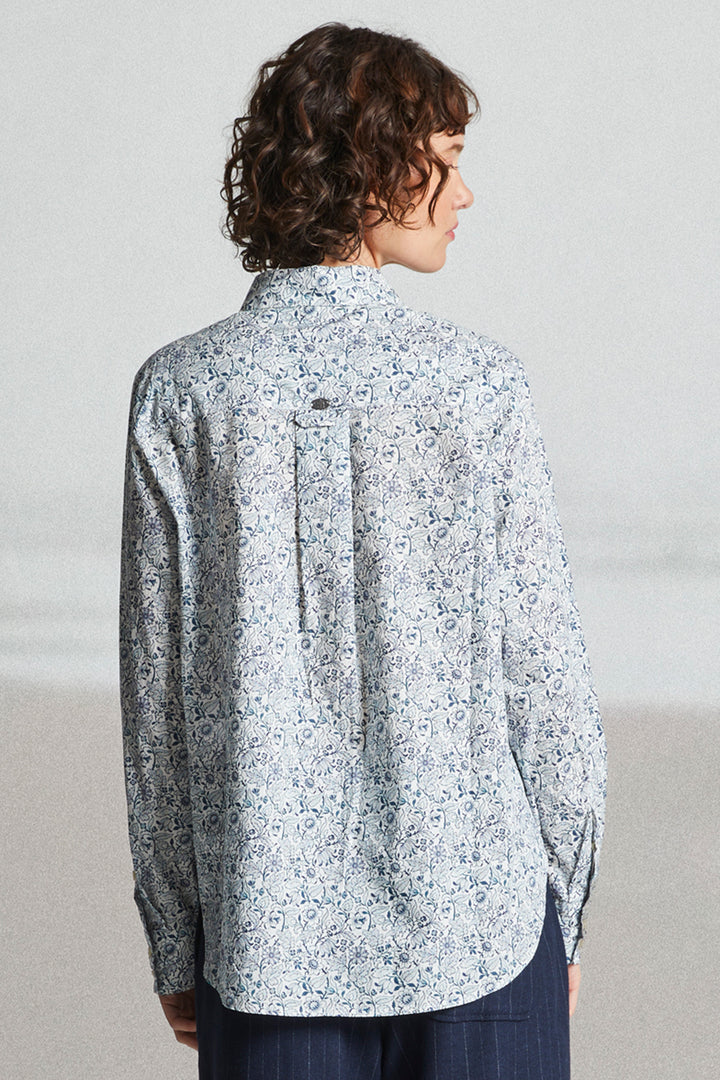 Person wearing a light blue floral shirt against a plain background